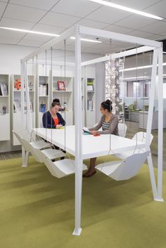 two people sitting at a white table in an office with green flooring and yellow carpet