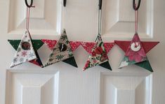 three origami stars hanging from hooks on a white door with red and green decorations