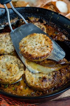 some food is being cooked in a skillet with a spatula and tongs