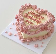 a heart shaped birthday cake with pink frosting