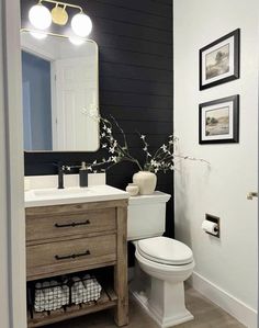 a white toilet sitting next to a wooden cabinet in a bathroom under a vanity mirror