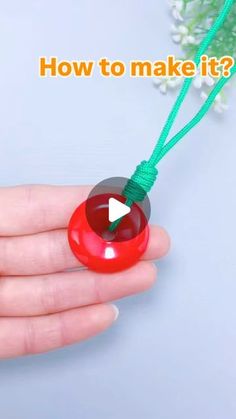 a hand holding a red object with a green string and the words how to make it?