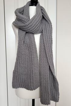 a gray knitted scarf sitting on top of a mannequin