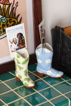 a pair of cowboy boots sitting on top of a green tiled floor next to a wall