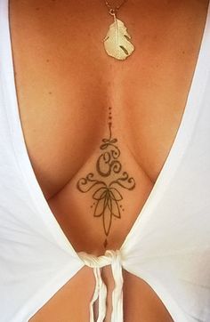 the back of a woman's white shirt with tattoos on her chest and neck