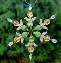 a glass ornament hanging from a tree with green and yellow beads on it