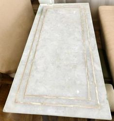 a white marble dining table with two beige chairs