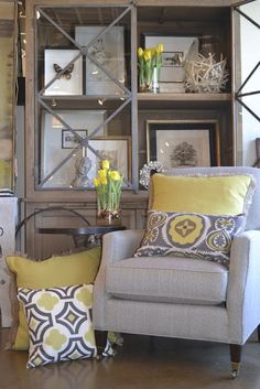 a living room filled with furniture and yellow flowers on top of a book shelf in front of a mirror