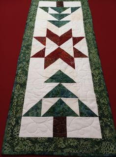 a quilted table runner with red, green and white stars on the center piece