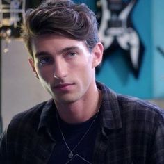 a young man is sitting down and looking at the camera while wearing a black shirt