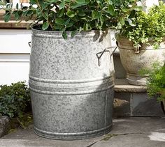 two large metal buckets with plants in them on the side of a house steps