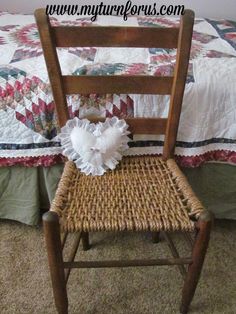 a wooden chair sitting in front of a bed with a quilt on top of it