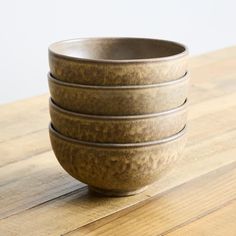 four brown bowls sitting on top of a wooden table