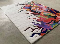 a multicolored rug on the floor in a room with concrete floors and walls