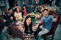 a group of people sitting at a table with plates and bowls in front of them