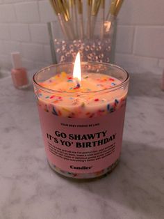 a candle that is sitting on a table with some candles in the background and confetti sticks sticking out of it