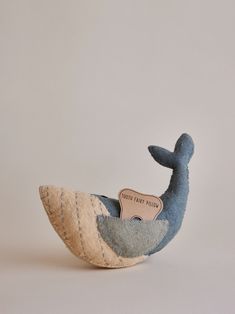 a stuffed whale with a wooden sign on it's back and its tail sticking out