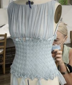 a woman is working on a dress made out of fabric