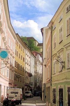 an empty street with cars parked on both sides and buildings in the backround