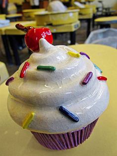 a cupcake with white frosting and sprinkles sitting on top of a table