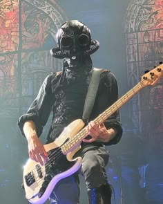 a man in a gas mask playing a bass guitar