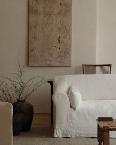 a white couch sitting next to a wooden table in front of a painting on the wall