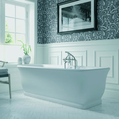 a white bath tub sitting under a window next to a chair and potted plant