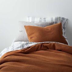 an orange and white bed with two pillows