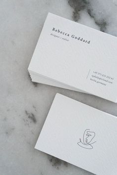 two white business cards sitting on top of a marble counter