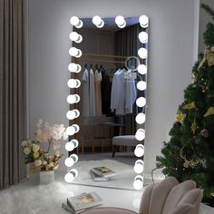 a mirror with lights on it in front of a christmas tree and a book sitting on the floor