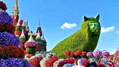 people are standing in front of the flower garden at disney world, which is decorated with flowers