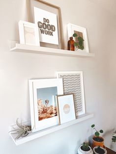 two white shelves with pictures and plants on them