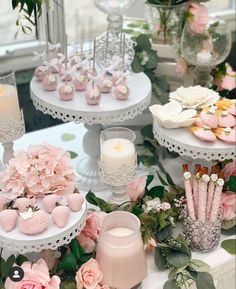 three tiered trays filled with cupcakes, cookies and flowers on a table