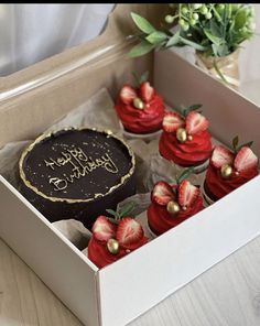 a box filled with cupcakes and strawberries on top of a wooden table