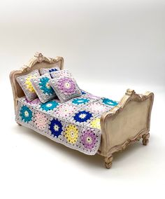 a crocheted bedspread and pillows on a white bed with wooden headboard