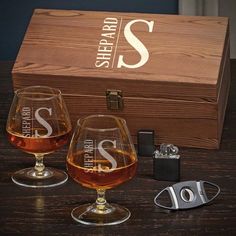 two wine glasses sitting on top of a table next to a wooden box and lighter