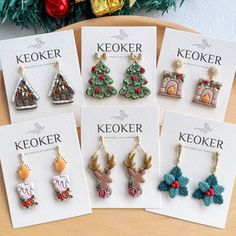 six christmas themed earrings are on display in front of a card with the words keoker