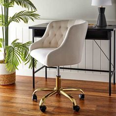 a white chair sitting on top of a wooden floor next to a potted plant