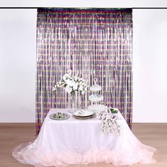 a table with plates and flowers on it in front of a curtain that is drapes