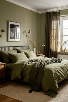 a bed with green sheets and pillows in a bedroom next to a window filled with plants