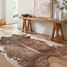 a brown and white rug sitting on top of a wooden floor next to a table