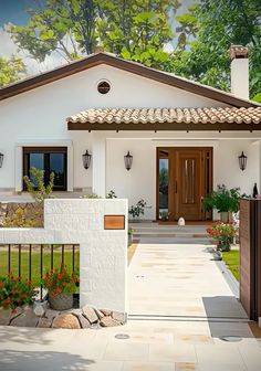 a white house with red flowers in the front yard and brown doors on both sides