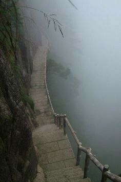 stairs lead down to the water on a foggy day at the edge of a cliff