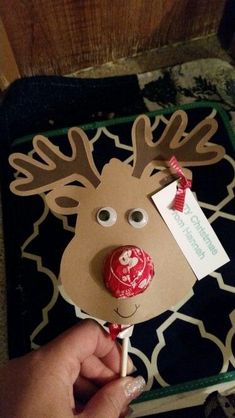 a hand holding a lollipop with a reindeer face on it