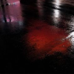 a wet street with red light reflecting off the pavement