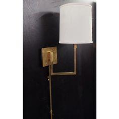 a wall lamp with a white shade on it's side against a black wall