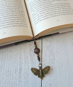 This item is not made until you order. Current processing is 2-3 weeks and takes into account the amount of orders ahead of yours.Introducing a truly unique beaded bookmark that will captivate any book lover! This piece features a stunning bronze plated hawkmoth charm gracefully dangling from a dark and mysterious strand of Gothic beads. The hawkmoth symbolizes transformation and boundless freedom. Each bead has been carefully selected to enhance the bookmark's dark, enigmatic allure. Whether yo Book Accessories Diy, Thread Bookmark, Bookmarks Jewelry, Aesthetic Bookmarks, Bookmarks Ideas, Wire Bookmarks, Gothic Literature, Diy Bookmark, Vintage Bookmarks