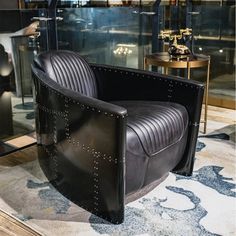 a black leather chair sitting on top of a rug next to a glass wall and floor