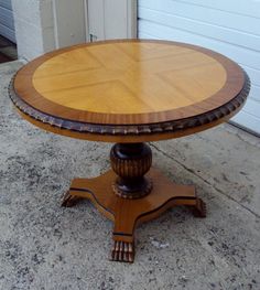 a round wooden table sitting on top of a cement floor next to a garage door