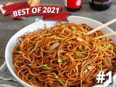 a white bowl filled with noodles and chopsticks on top of a wooden table